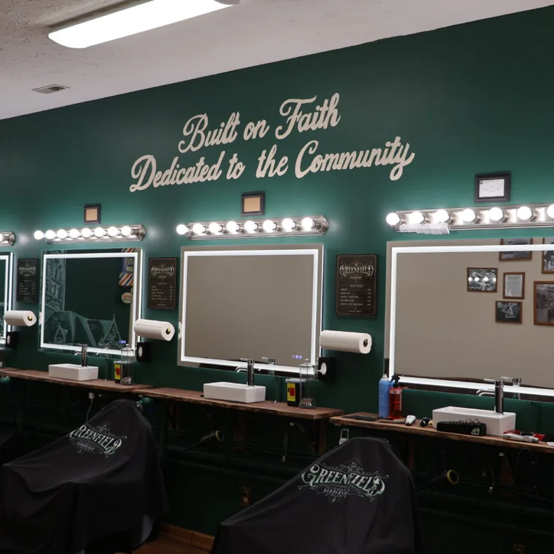 A row of backlit mirrors and framed service signs along the green wall